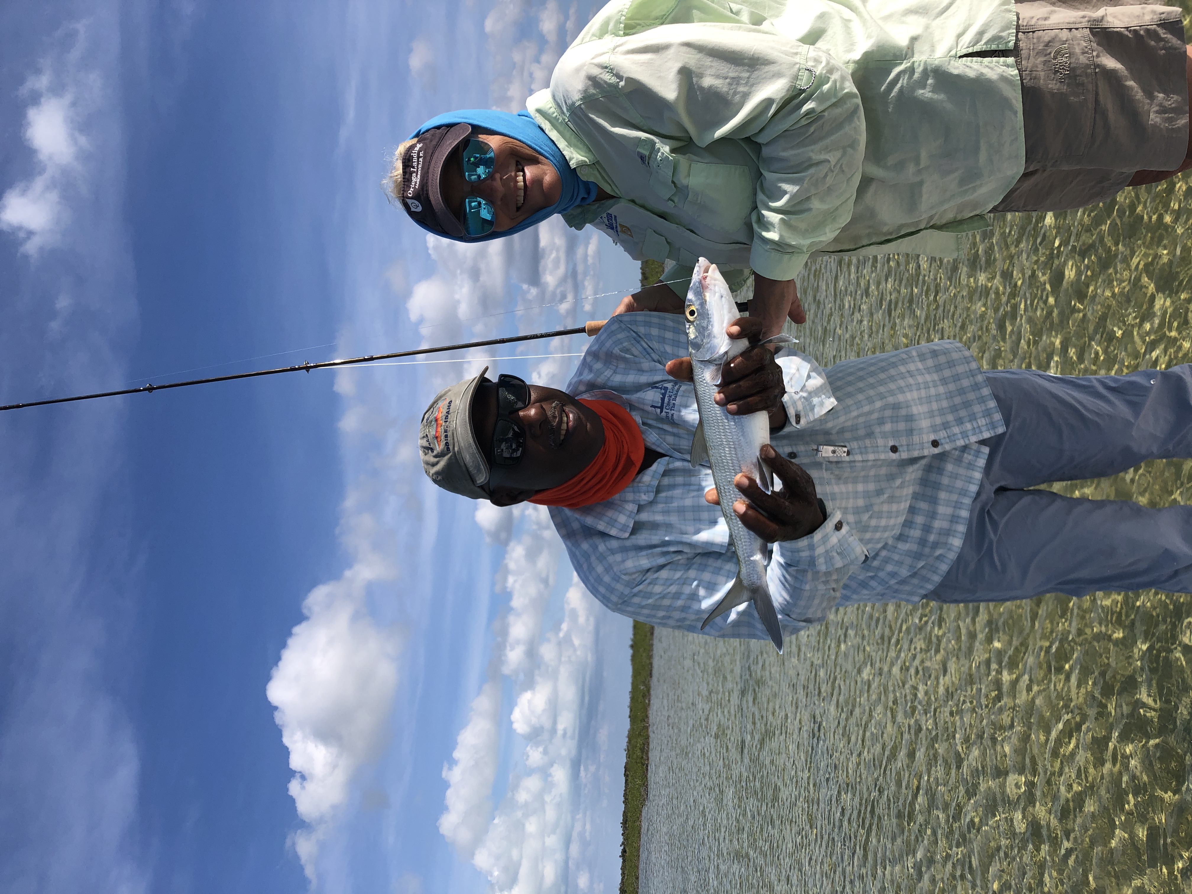 Two anglers holding a bonefish catch on the crystal clear flats of Andros Bahamas