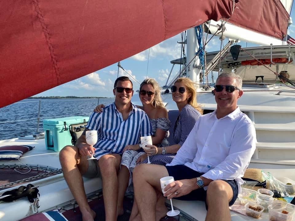 Two couples enjoying wine and snacks on the deck of Now and Zen sailing catamaran Jacksonville